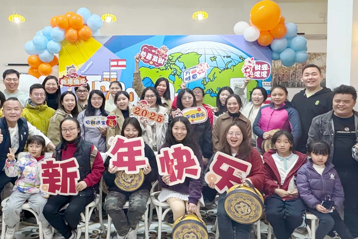 Group photo of diverse team members in front of company banner