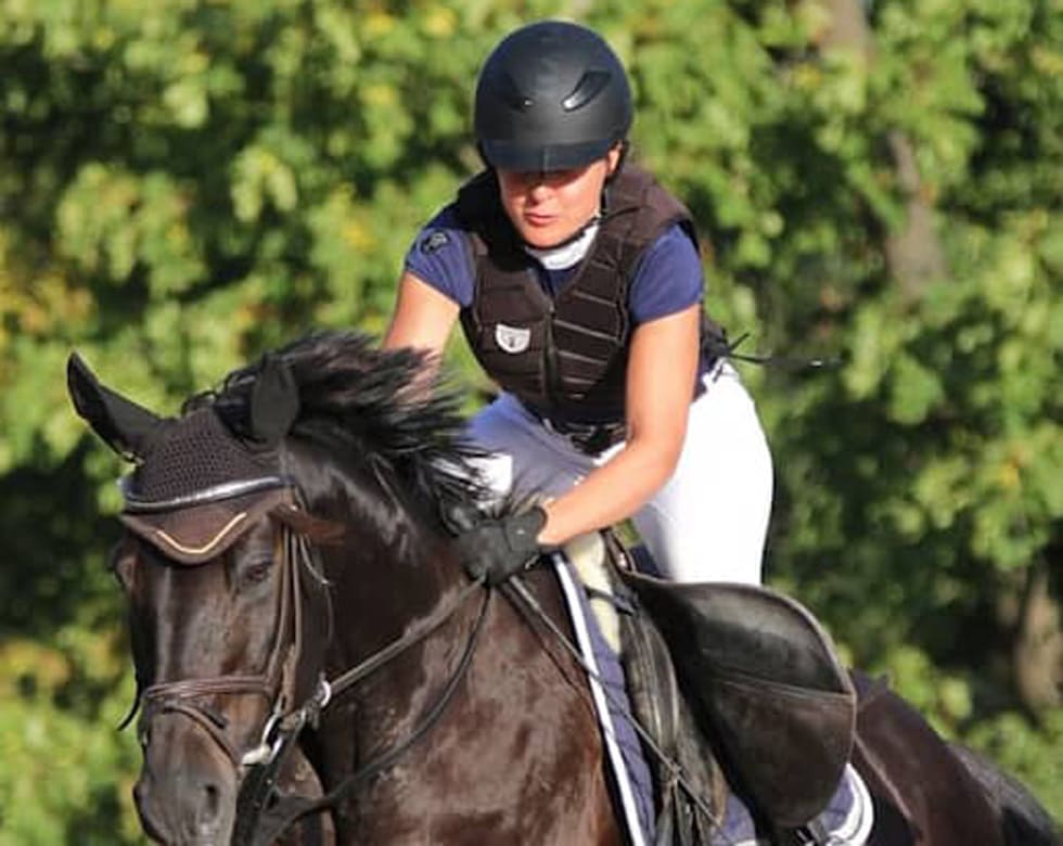 Young rider in white shirt on a white horse with red saddle pad