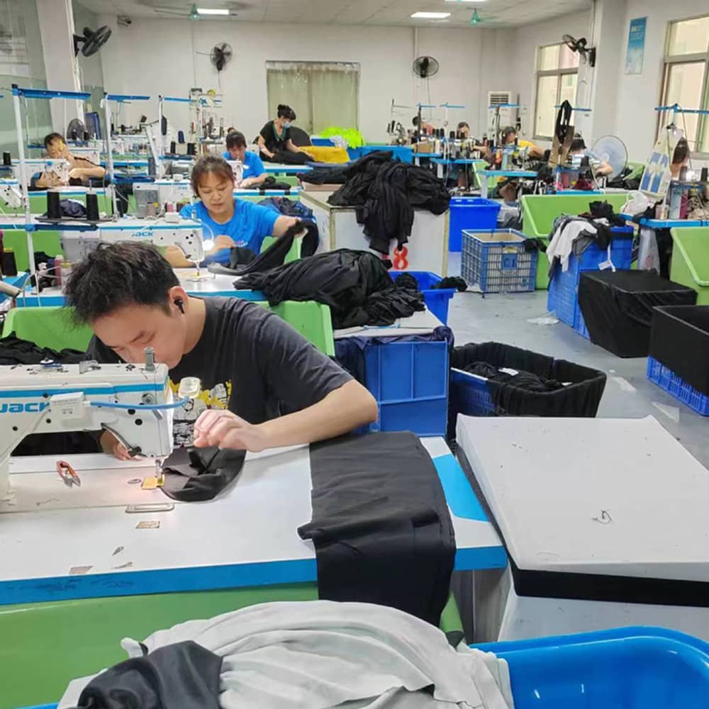 Manufacturing facility showing workers at workstations with blue and green containers, sewing machines, and various equipment for producing equestrian products