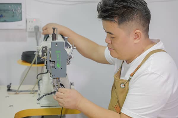 Craftsman in apron working with precision equipment on equestrian gear